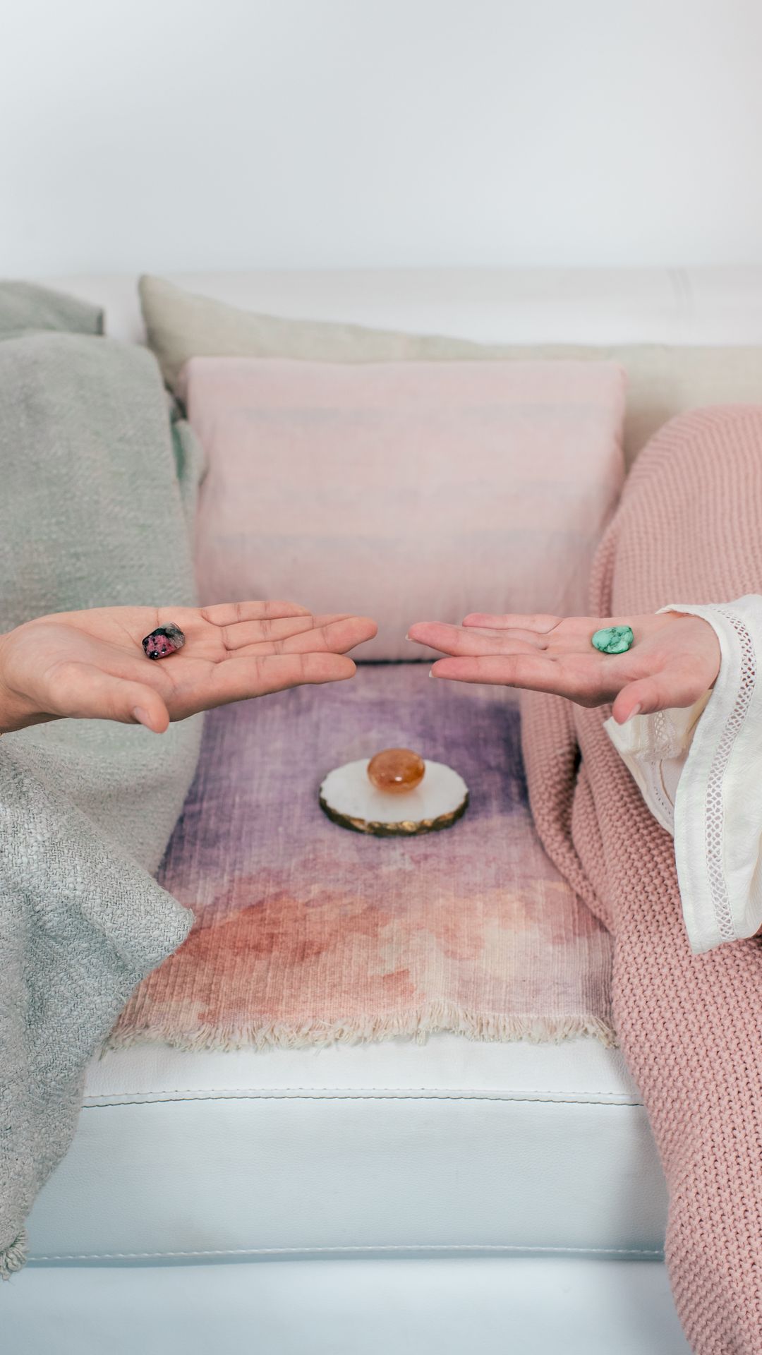 Two hands resting together beside rose quartz